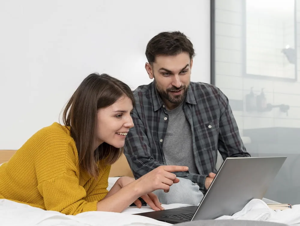 Couple pointing at a laptop screen together