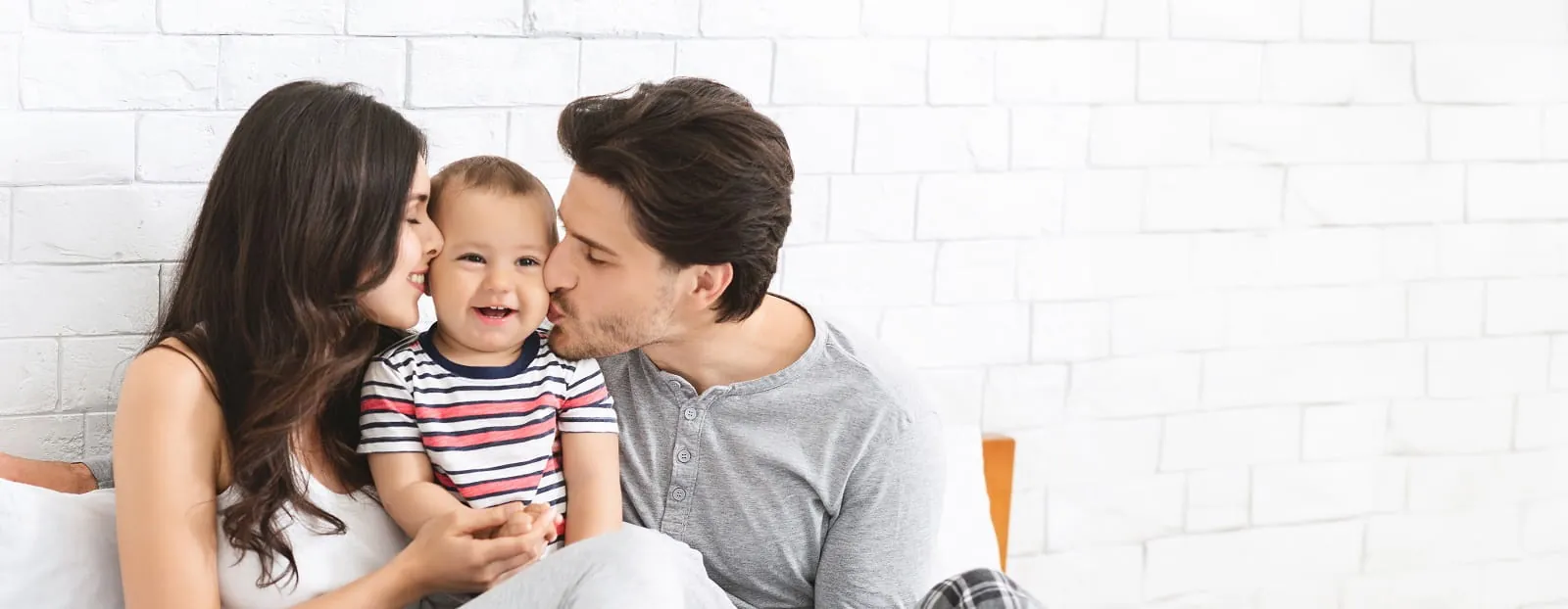 Parents kissing their smiling baby