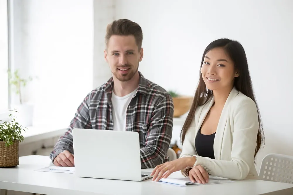 Man and woman smiling at a laptop at an office desk