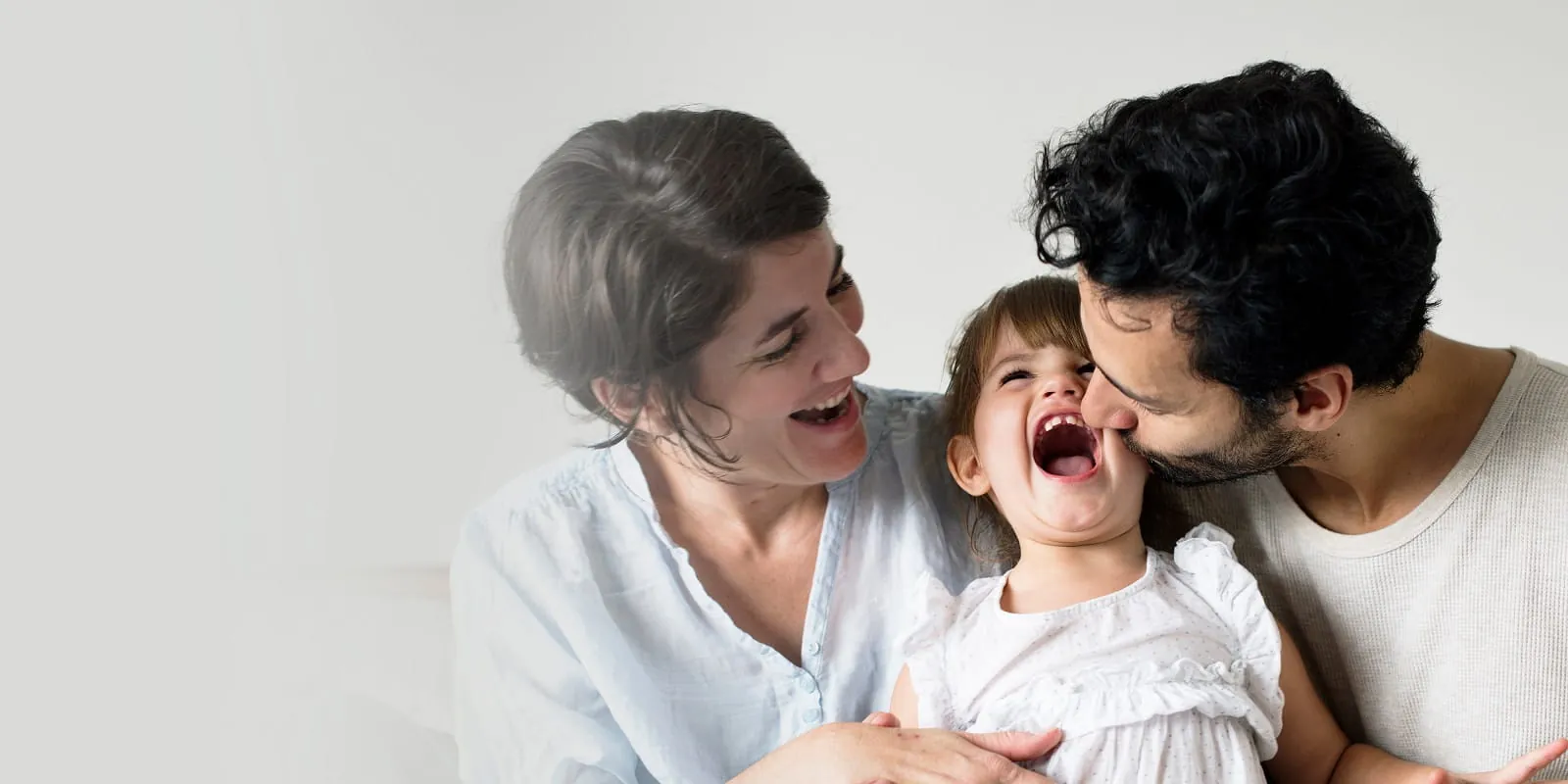 Parents hugging their laughing child
