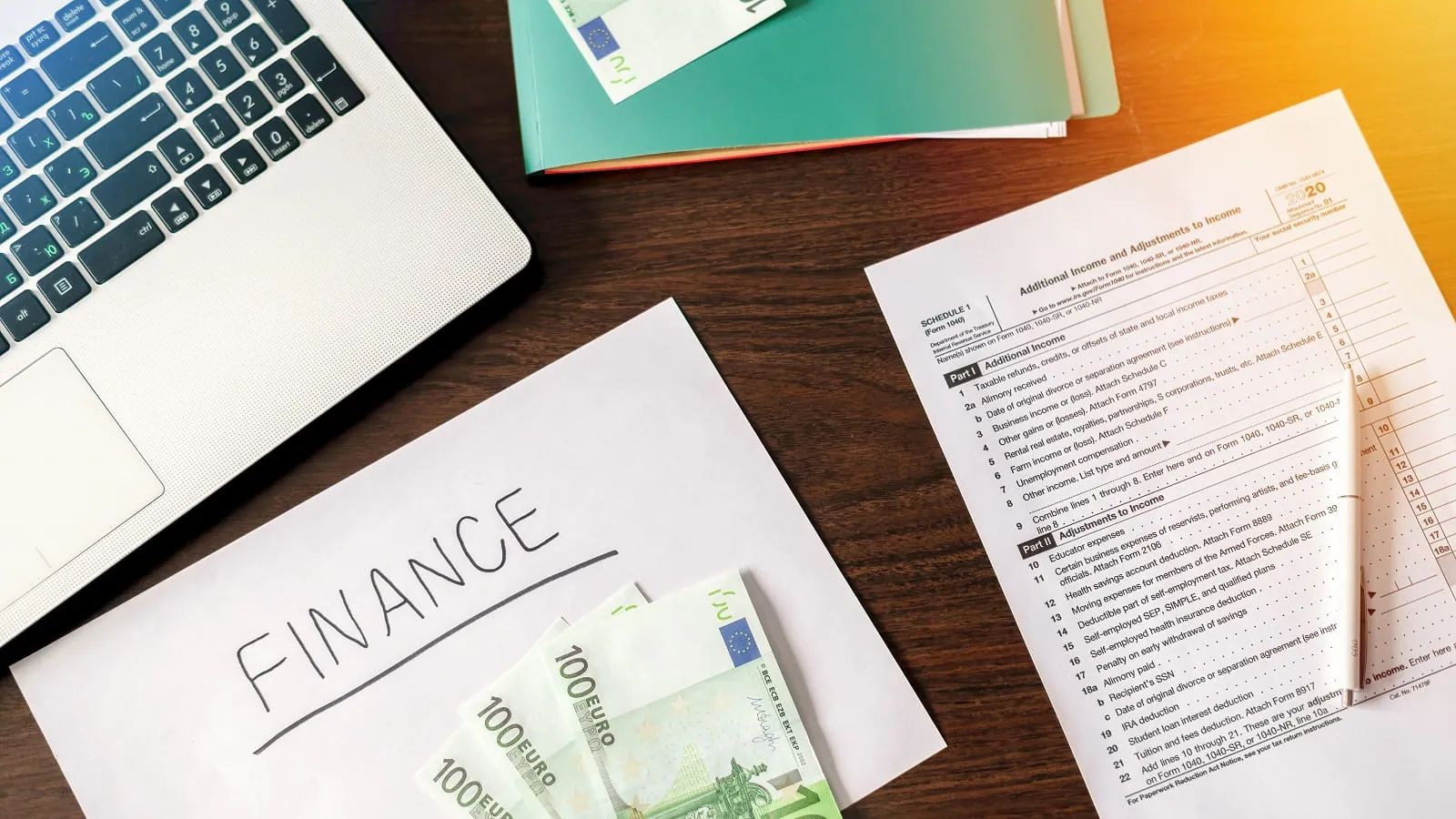 Finance papers, laptop and cash on a desk