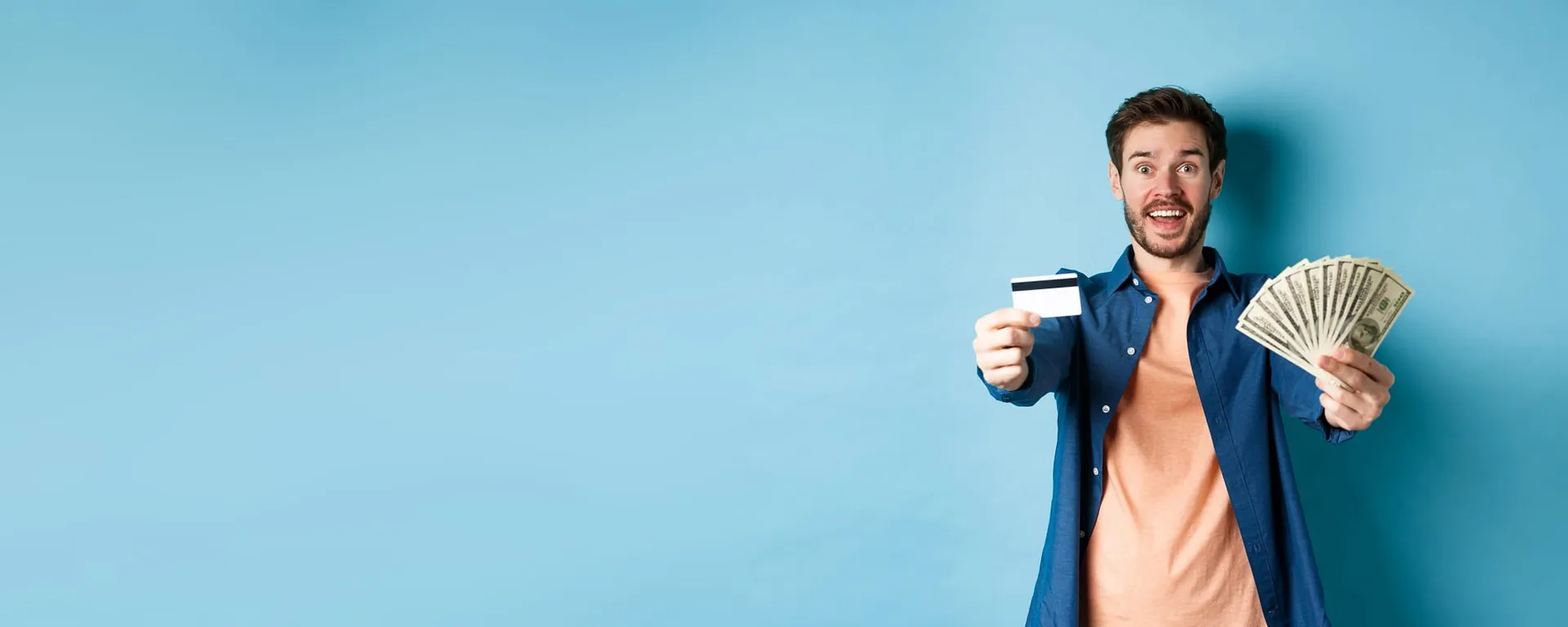 Excited man holding a card and cash against a blue background