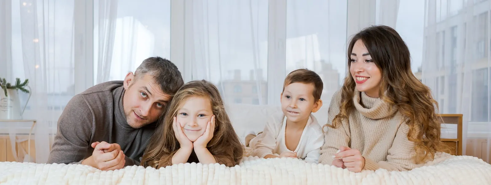 Family of four relaxing together on a bed