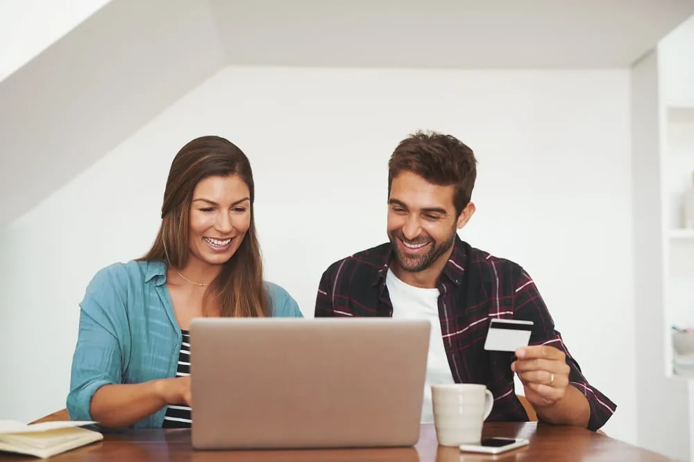 Couple using a laptop and a card at home